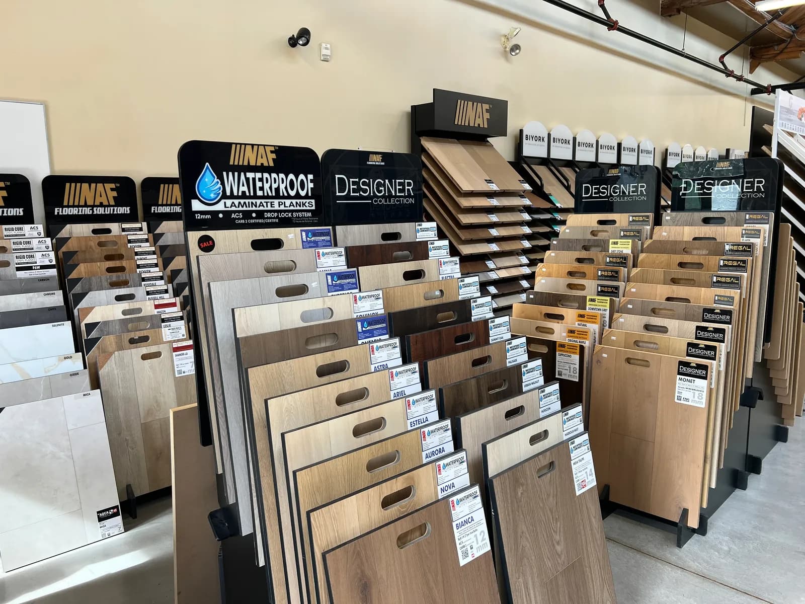 Racks of laminate and engineered hardwood sample boards, each with its name and grade on a label.